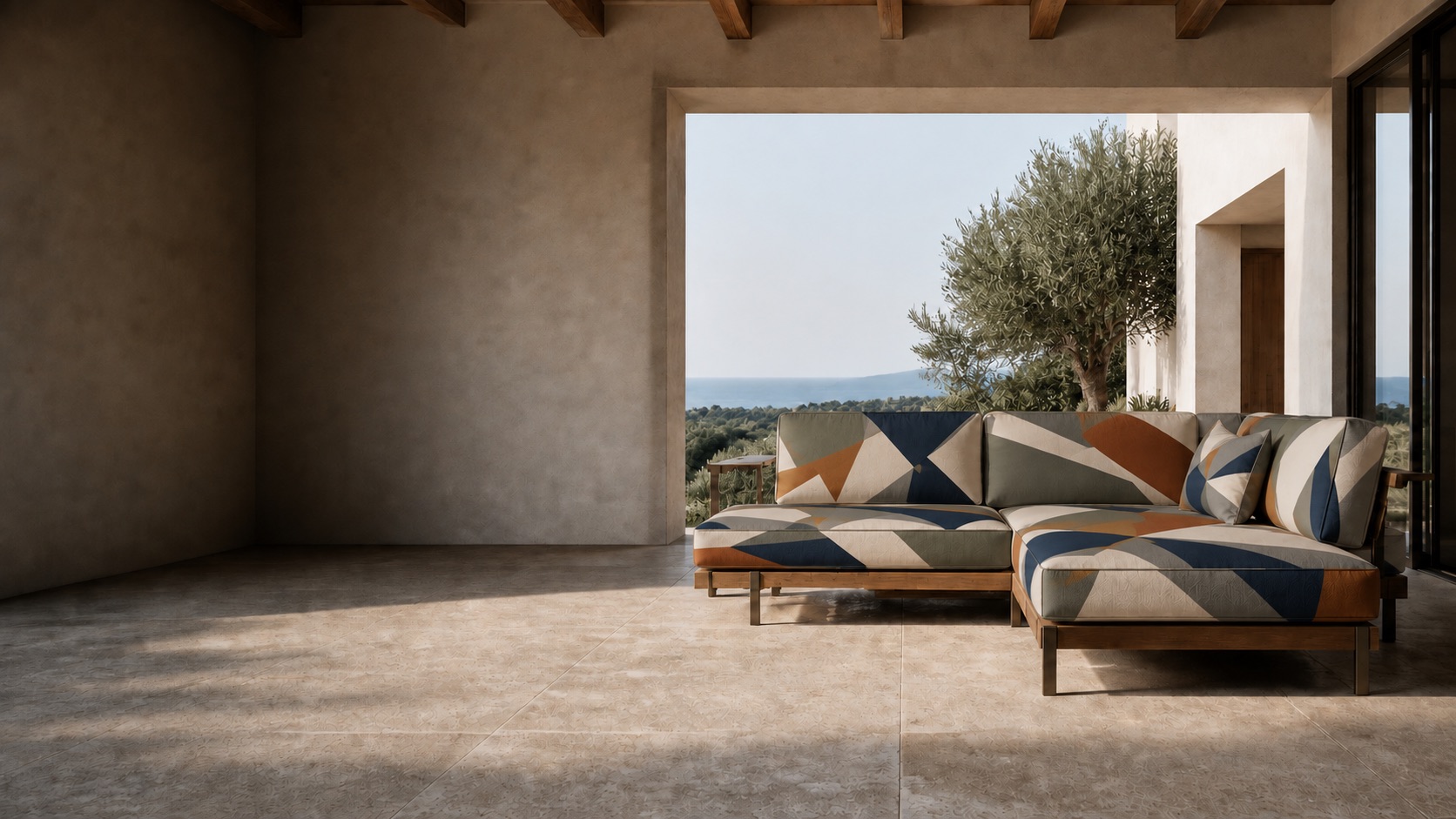 Outdoor terrace seating upholstered in the SOLSTICE design, with an olive tree and the sea beyond.